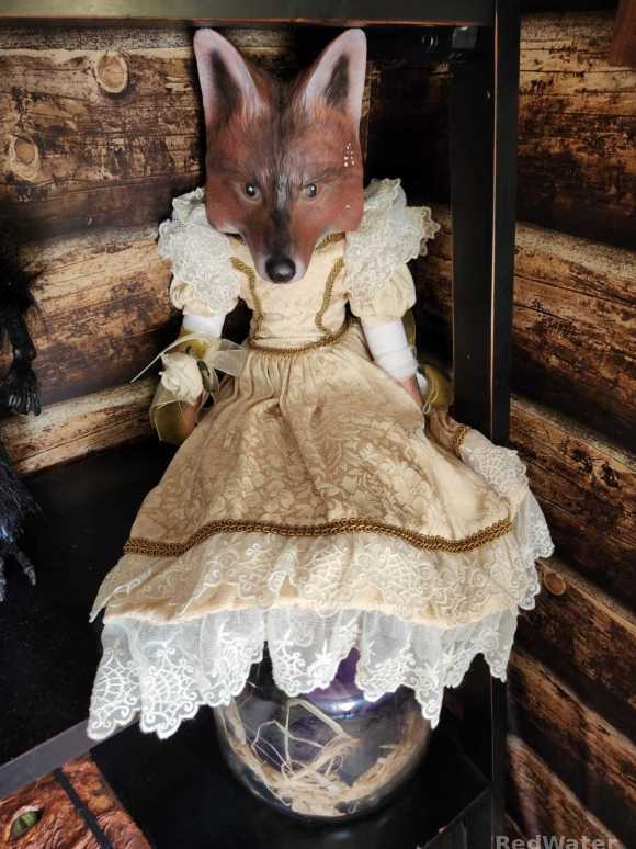 A wolf's head sitting atop a human-like figure in a frilly dress