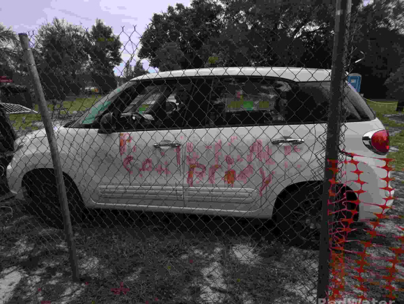 A white car with a message scrawled on it in what appears to be blood.