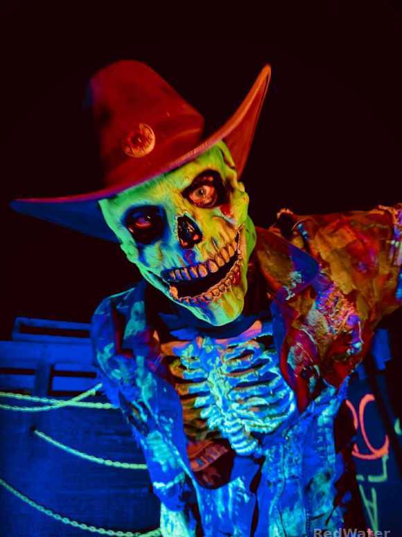 A bright green skeleton dressed in camouflage and a cowboy hat.
