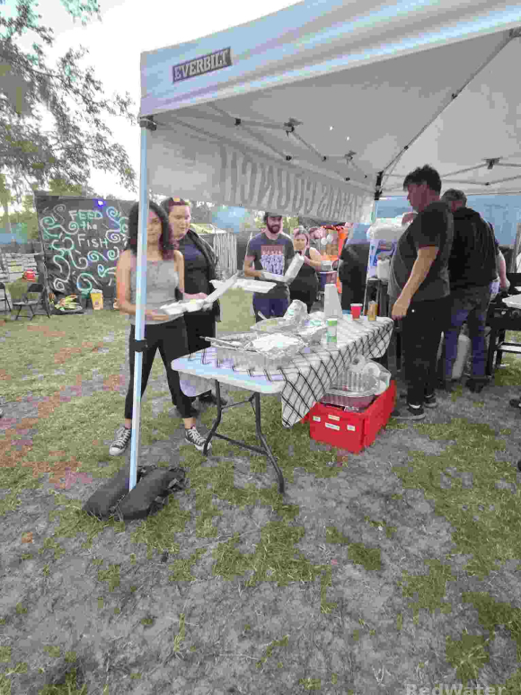 Several people are seen serving themselves from a small buffet-style table